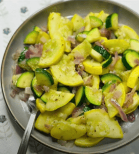 Picture of healthy and delicious sauteed green zucchini and yellow squash with fresh herbs on a plate with a fork.