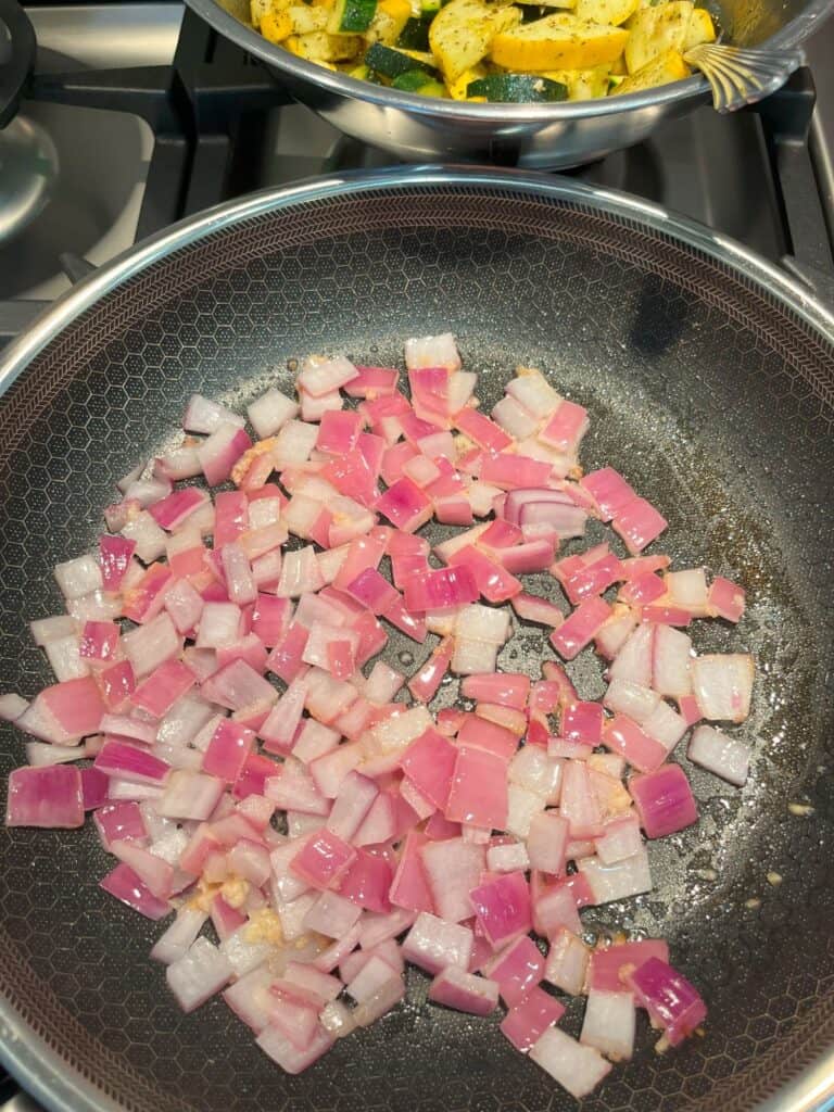 FBB_Side.Butter.Onion.Garlic.Saute.Translucent.1200x1600. Translucent photo of red onion and garlic sauteing butter in a frying pan on the stove.