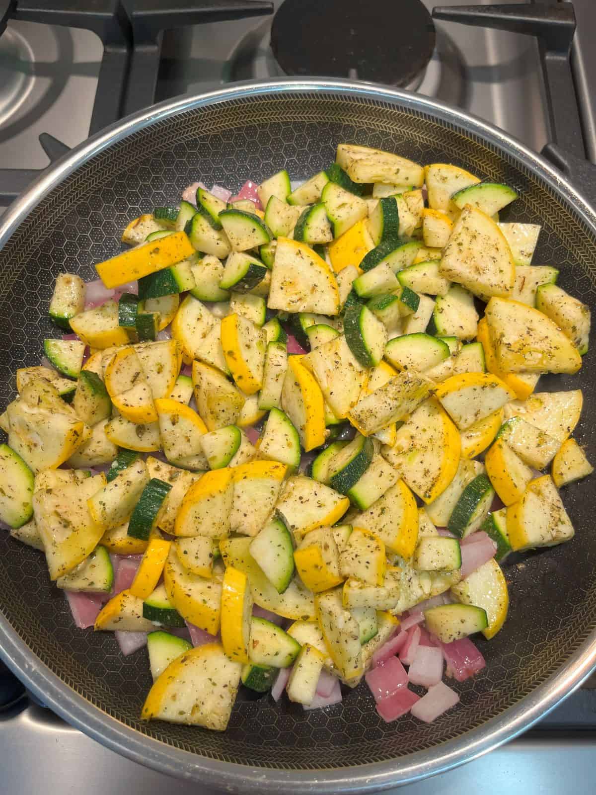 FBB_Side.Zucchini.Squash.Saute.Saute.1200x1600. This is a photo of the seasoned zucchini and yellow squash added to the frying pan of sautéed red onion and garlic on the stove,