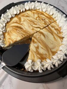 Homemade pumpkin pie and cheesecake swirl with whipped cream boarder in pie pan, ready to serve.