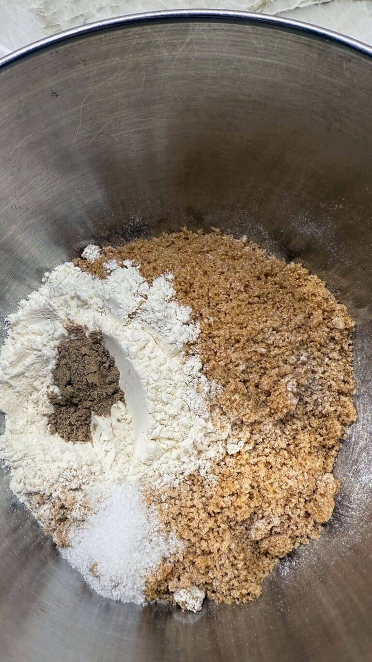 Dry baking ingredients—flour, sugars, and spices—arranged separately in a mixing bowl before combining.