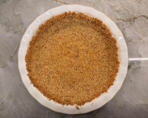 Homemade walnut pie crust in white ceramic 9-inch pie plate on kitchen counter