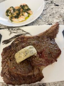 Juicy Baked Bone-In Ribeye Steak on a platter with herbed butter.