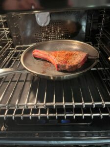 Bone-in ribeye steak cooked in a pan and then placed in the oven to finish cooking.