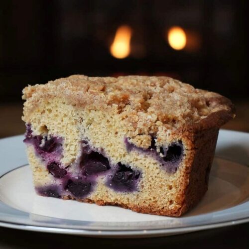 Moist blueberry crumb cake with streusel topping on a white and blue China plate