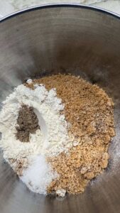 Dry baking ingredients—flour, sugars, and spices—arranged separately in a mixing bowl before combining.