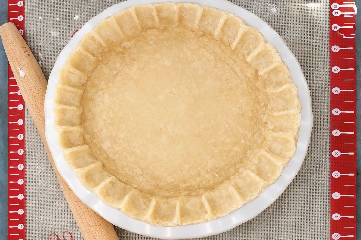 Unbaked pie crust pressed into a pie dish with crimped edges.