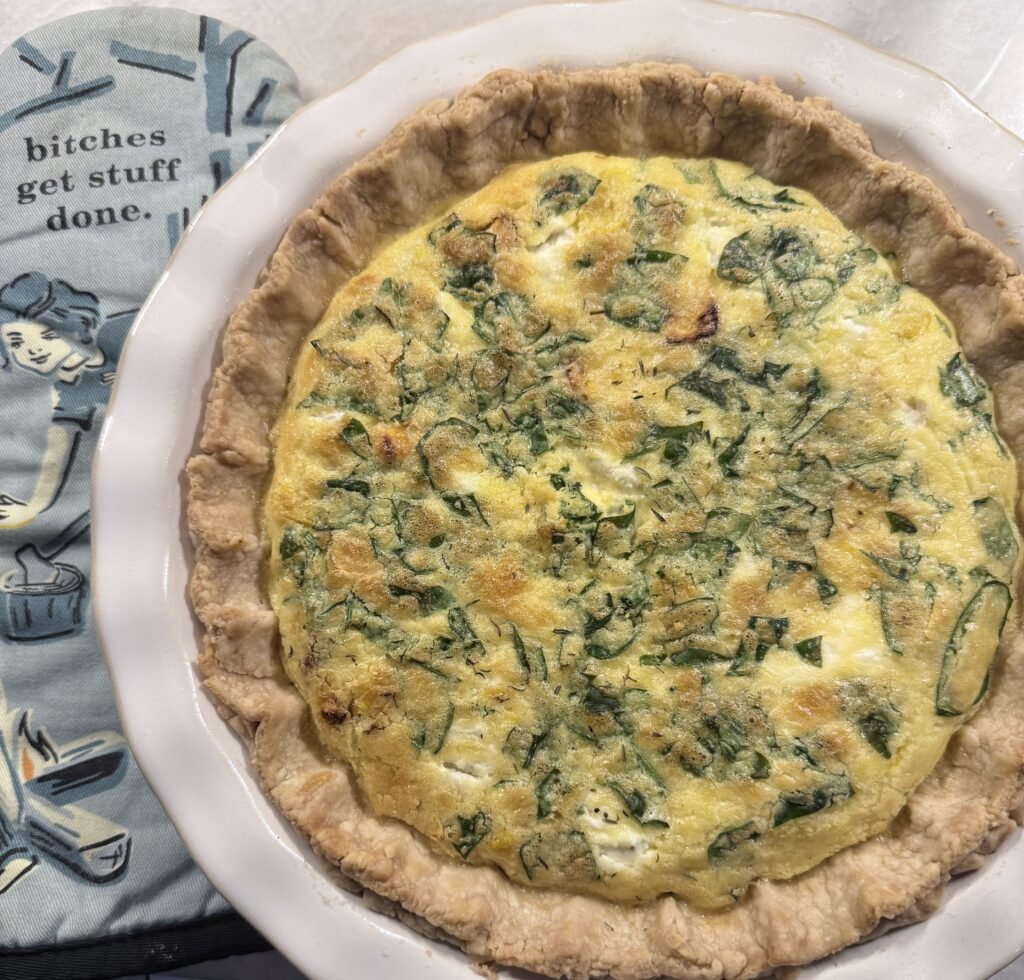 Fully baked quiche with a creamy vegetable filling inside a golden pie crust.