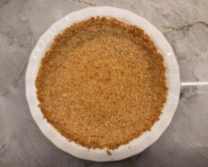 Homemade walnut pie crust in white ceramic 9-inch pie plate on kitchen counter