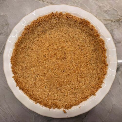 Homemade walnut pie crust in white ceramic 9-inch pie plate on kitchen counter
