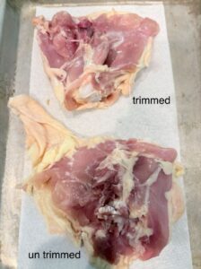 Two raw poultry pieces on a white surface, showing an untrimmed piece next to a trimmed piece with excess fat removed