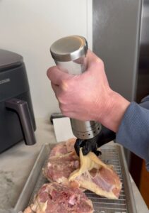 Close‑up of seasoning raw chicken pieces on a wire rack, lifting the skin to apply spices evenly.