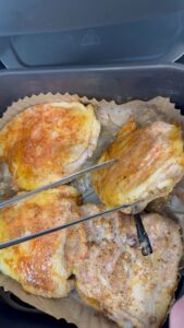 Seasoned chicken thighs cooking on parchment with temperature probes inserted to monitor doneness.