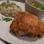 A plated meal with air fryer fried chicken, herbed rice, and a small bowl of fresh mixed salad with diced vegetables.