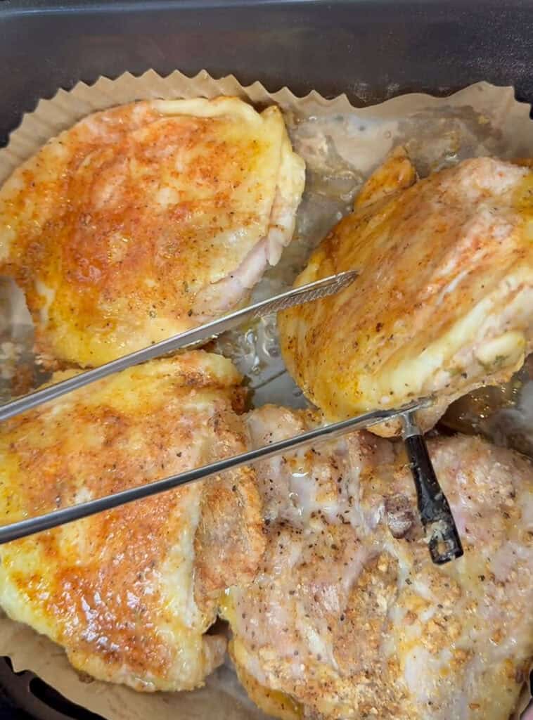 Seasoned chicken thighs cooking on parchment with temperature probes inserted to monitor doneness.