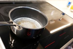 Boiling sugar and water in a pan to make baklava syrup before adding orange blossom water.