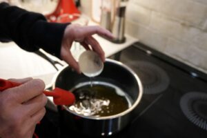 Pouring orange blossom water into a saucepan of hot simple syrup for baklava.