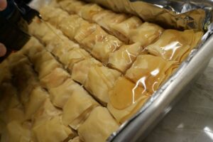 Pouring orange blossom water–infused syrup over freshly baked baklava.