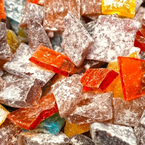 Colorful pieces of assorted hard candy coated in powdered sugar, arranged closely together.