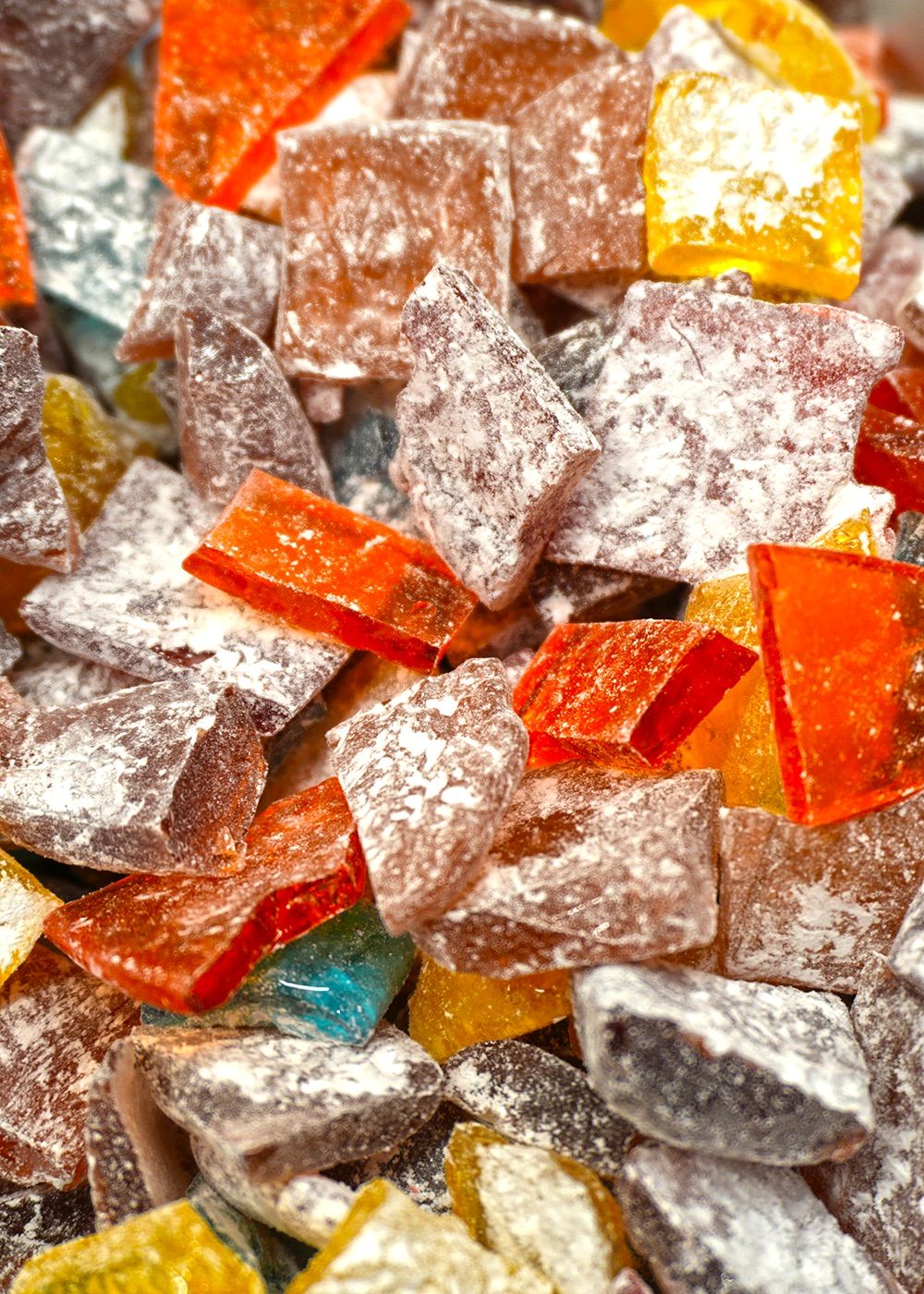 Colorful pieces of assorted hard candy coated in powdered sugar, arranged closely together.