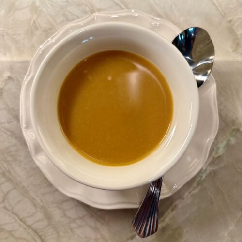 Cup of honey‑miso sauce on a light surface with a spoon beside it.