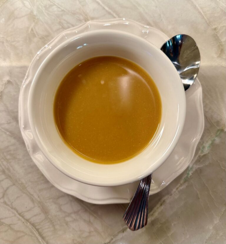 Cup of honey‑miso sauce on a light surface with a spoon beside it.