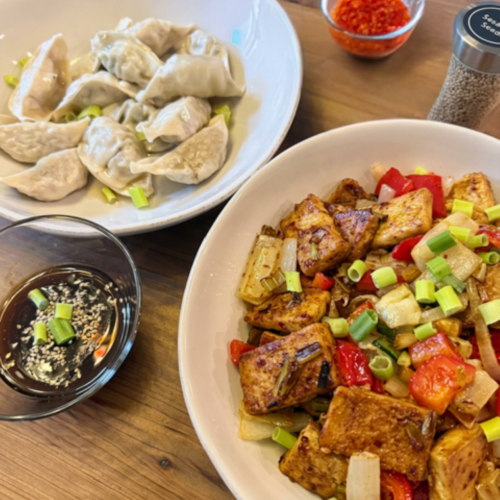 Sweet spicy stir‑fry and dipping sauce served with crispy tofu, dumplings, and fresh vegetables.
