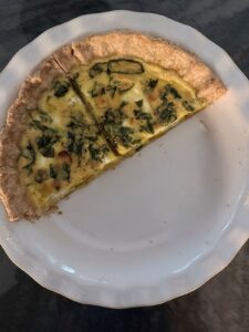 Two slices of baked quiche on a white pie plate with a golden, tender interior.