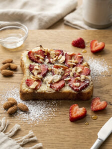 Slice of strawberry almond croissant toast topped with fresh strawberries and sliced almonds.