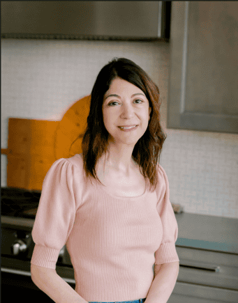 Samantha smiling in a soft pink top, photographed indoors for her Full Bloom Bites About Page.