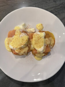 Assembled Eggs Benedict with hashbrown base, lox, poached egg, hollandaise, and paprika for Step 8