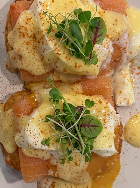 Assembled Eggs Benedict with hashbrown base, lox, poached egg, hollandaise, paprika, and microgreens for Step 9