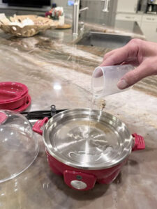 Boiling tray set on the heating plate with water added for poaching eggs in the Dash Rapid Egg Cooker