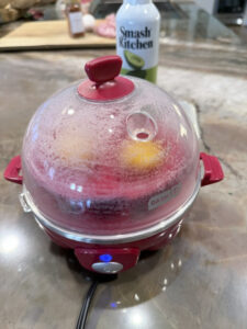 Dash Rapid Egg Cooker covered with the lid while the eggs cook for Step 6