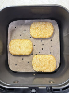 Hashbrowns arranged in an air fryer basket before cooking