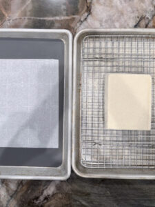 How to press tofu without a tofu press using two half sheet pans, a wire rack, and parchment paper